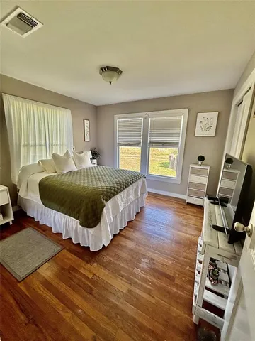 a spacious bedroom with a bed and wooden floor