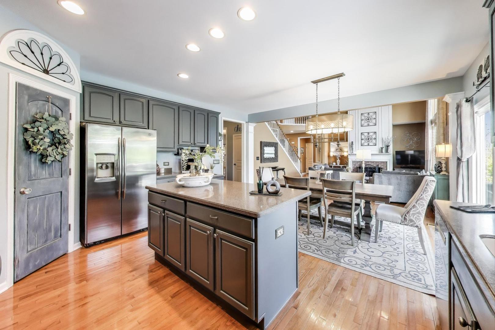 705 Porter Circle Lindenhurst, IL 60046 - Photo 6 of 34 a kitchen with stainless steel appliances granite countertop a refrigerator a sink dishwasher a dining table and chairs with wooden floor