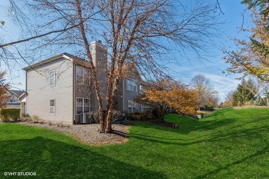 560 Lancaster Drive Pingree Grove, IL 60140 - Photo 21 of 26 a view of a white house with a big yard and large tree