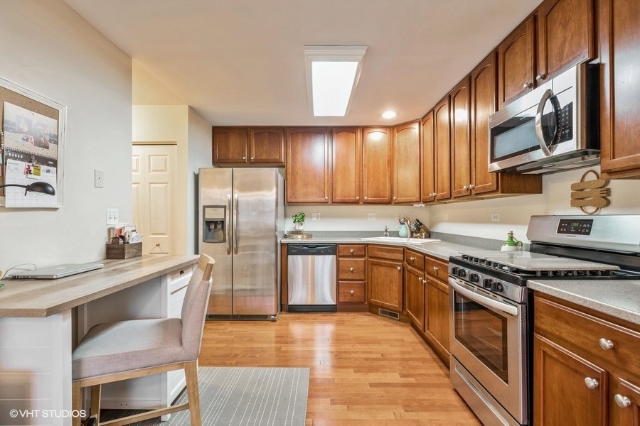 560 Lancaster Drive Pingree Grove, IL 60140 - Photo 5 of 26 a kitchen with stainless steel appliances granite countertop a stove top oven a sink dishwasher a refrigerator and cabinets with wooden floor