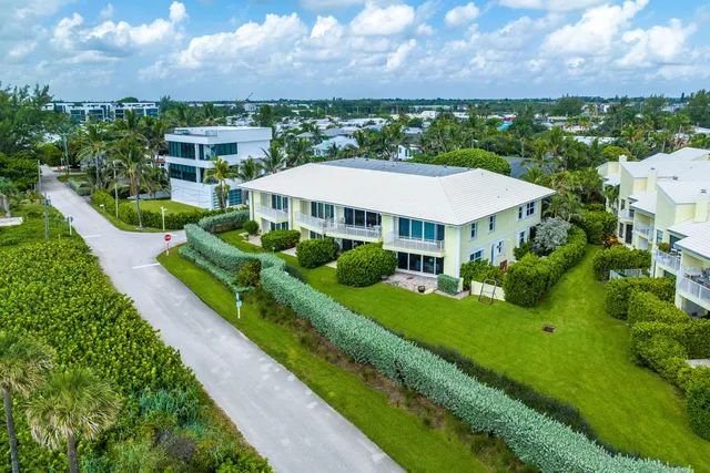 a view of a white house with a big yard and potted plants