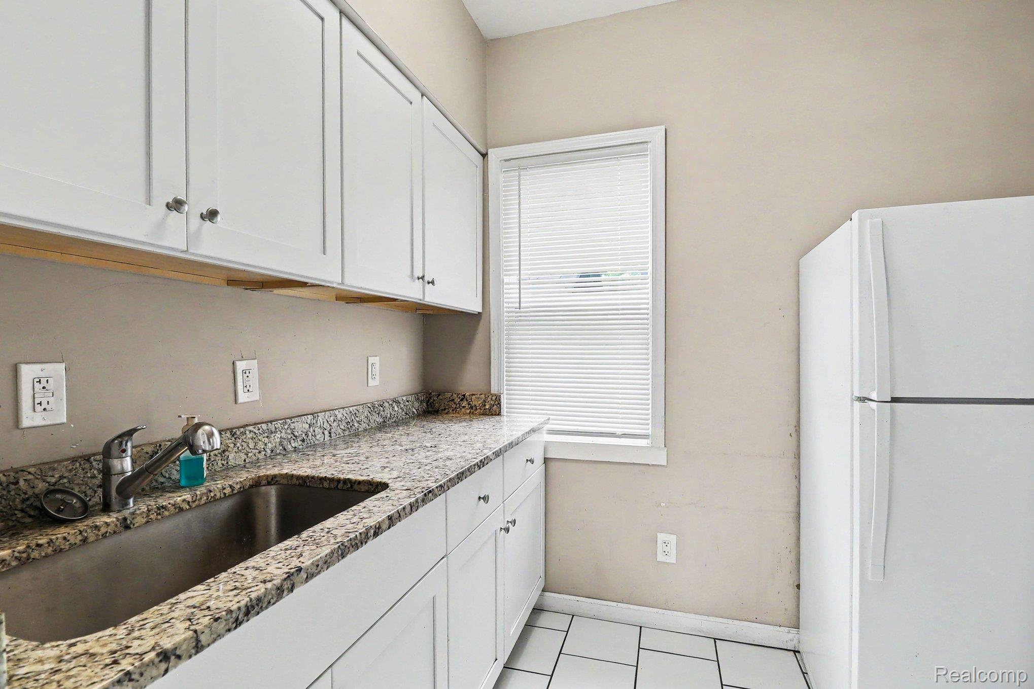7743 Pitt Street Detroit, MI 48209 - Photo 7 of 15 Kitchenette featuring white cabinetry, a stainless steel sink with a pull-down faucet, stone-finish countertops, and white tile flooring
