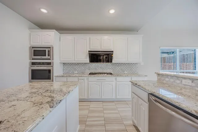 a kitchen with granite countertop a sink stove and microwave