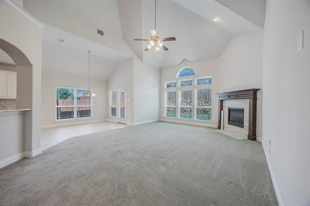 a view of an empty room with a window and kitchen view