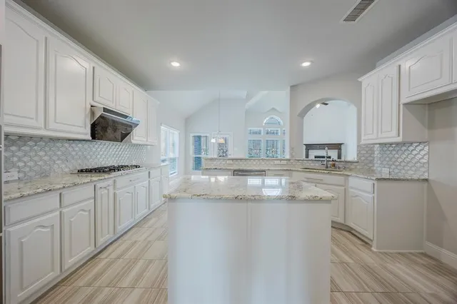 a kitchen with kitchen island granite countertop a sink and cabinets