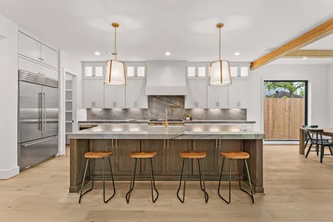 a kitchen with kitchen island granite countertop a table chairs sink and cabinets