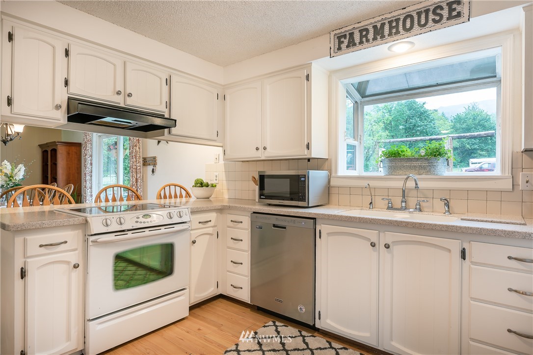 6820 Goodwin Road Everson, WA 98247 - Photo 8 of 34 a kitchen with stainless steel appliances granite countertop a sink a stove a refrigerator and cabinets with wooden floor