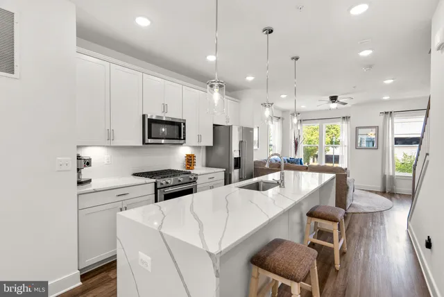 a kitchen with stainless steel appliances granite countertop a stove a sink a microwave a dining table and chairs