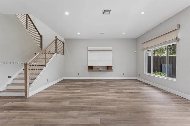 a view of empty room with wooden floor and fan