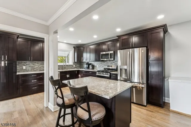 a kitchen with granite countertop kitchen island stainless steel appliances cabinets a sink and a counter top space