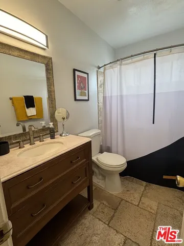 a bathroom with a granite countertop sink a toilet and a mirror