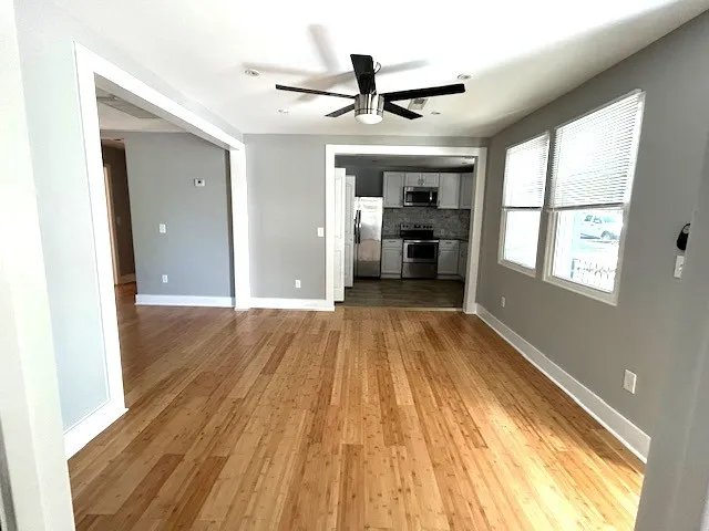 a view of a room with wooden floor a ceiling fan and windows
