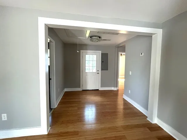 a view of a hallway with wooden floor and a bathroom