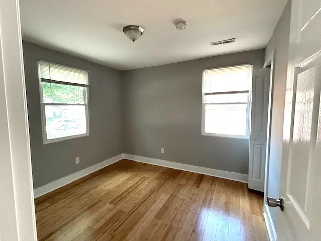 an empty room with wooden floor and windows