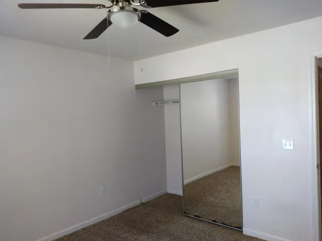 an empty room with a ceiling fan and carpet