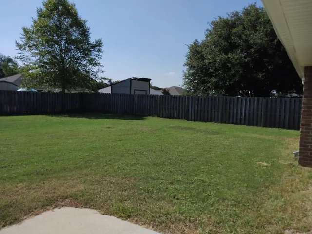 a view of backyard with wooden fence