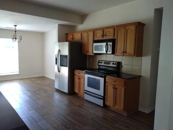 a kitchen with a refrigerator stove and wooden floor