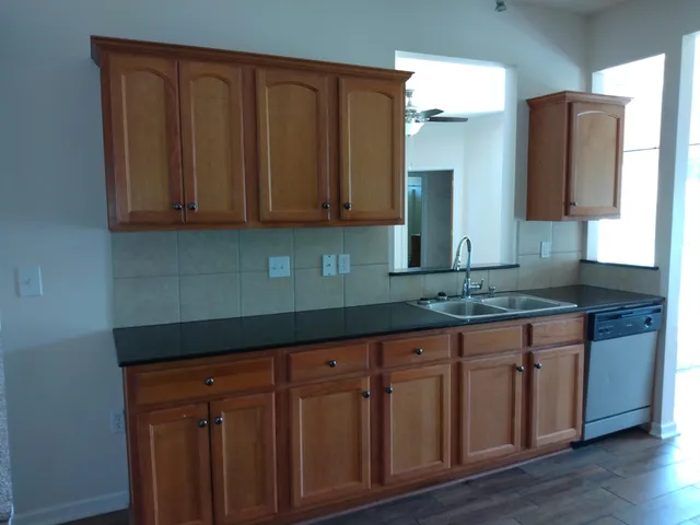 a kitchen with granite countertop wooden cabinets a sink and dishwasher