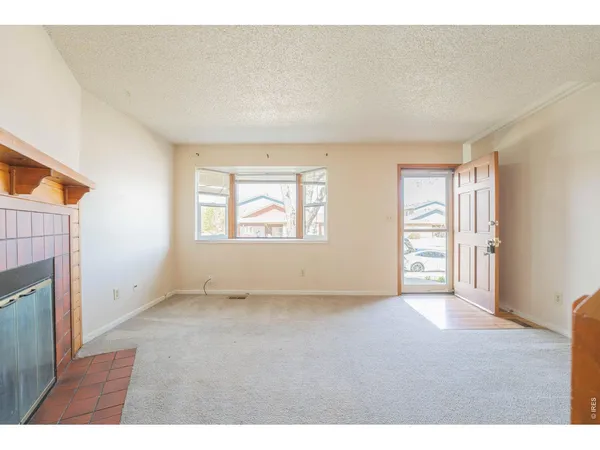 a view of an empty room with a window and fireplace
