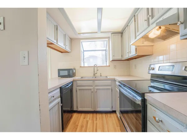 a kitchen with a sink cabinets stainless steel appliances and a window