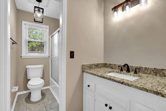 a bathroom with a granite countertop sink a toilet and a mirror