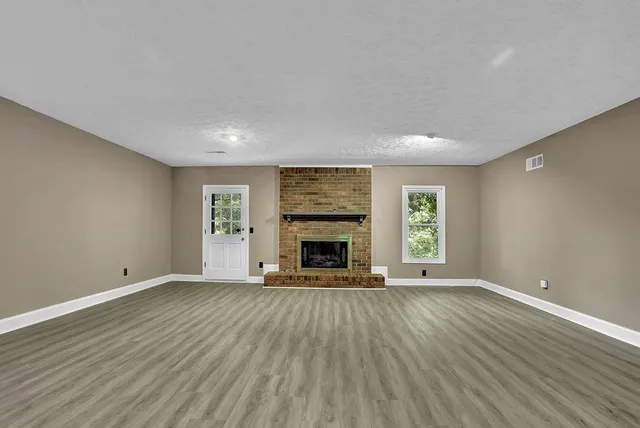 a view of an empty room with a window and fireplace