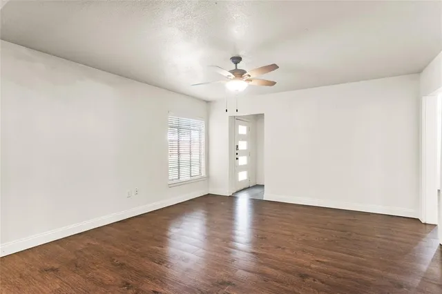a view of an empty room with a window and wooden floor