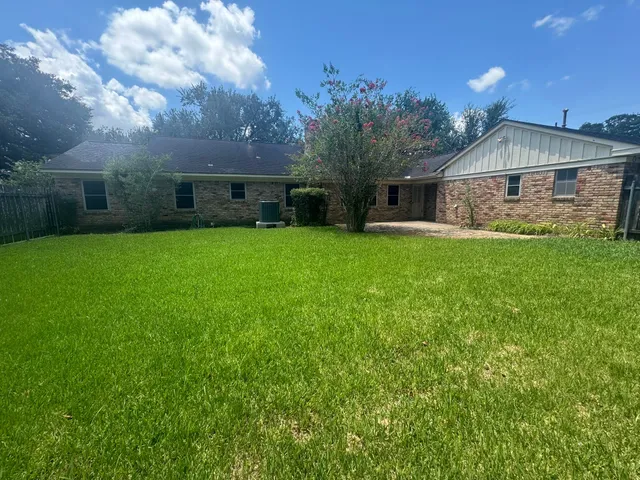 a view of a house with a yard and large tree