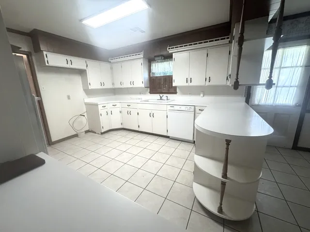 a large white kitchen with a sink a stove a refrigerator and cabinets