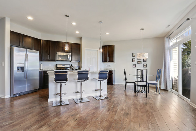 2816 Church Road Aurora, IL 60502 - Photo 7 of 20 a kitchen with stainless steel appliances kitchen island granite countertop a refrigerator a stove a dining table and chairs with wooden floor
