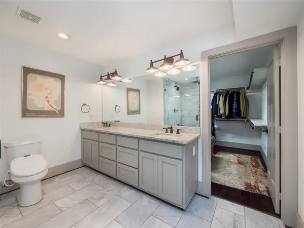 a spacious bathroom with a double vanity sink a large mirror and toilet