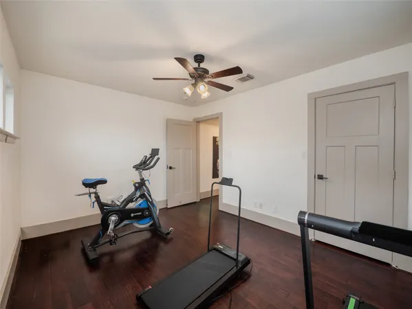 a room with gym equipment and wooden floor
