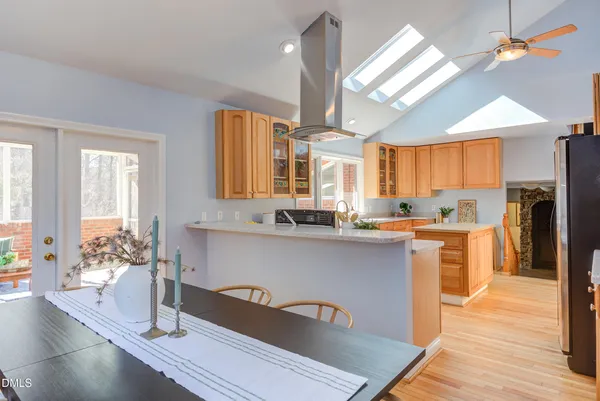 a dining room with stainless steel appliances kitchen island granite countertop a table chairs and a refrigerator