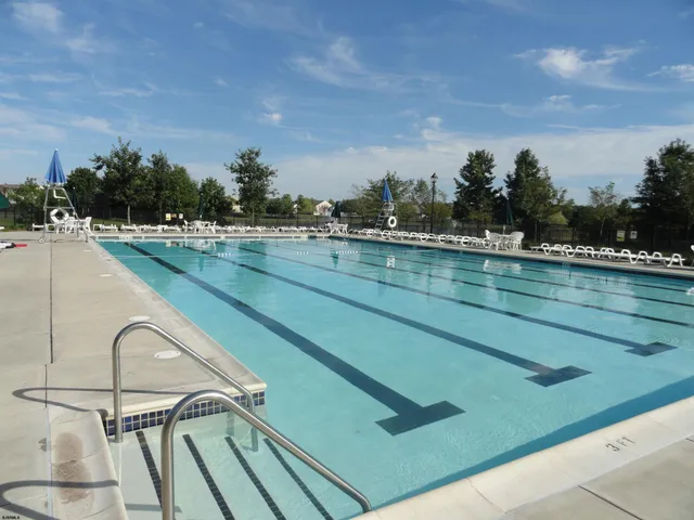 a view of a swimming pool with seating area and trees in the background