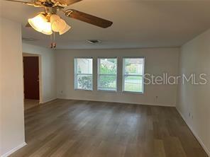 8873 Tami Street Seminole, FL 33772 - Photo 4 of 26 an empty room with wooden floor chandelier fan and windows