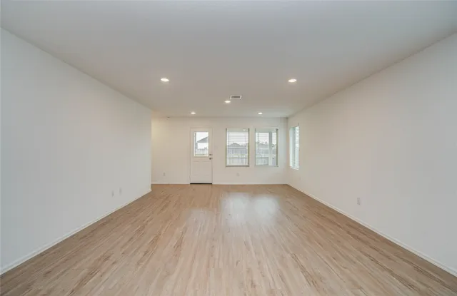 a view of an empty room with wooden floor and window