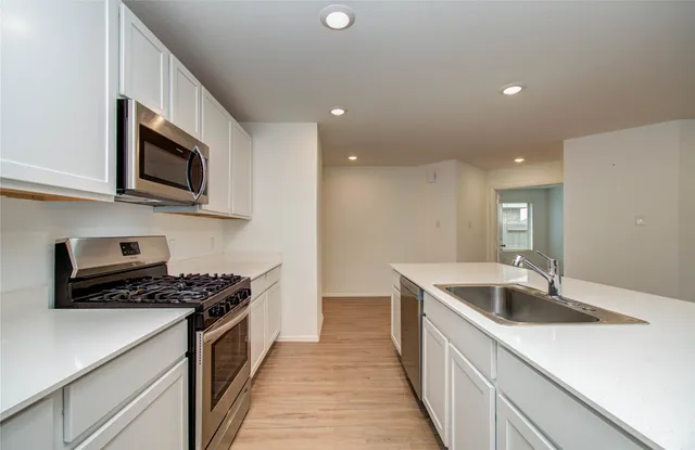 a kitchen with stainless steel appliances a sink a stove top oven a counter space and cabinets