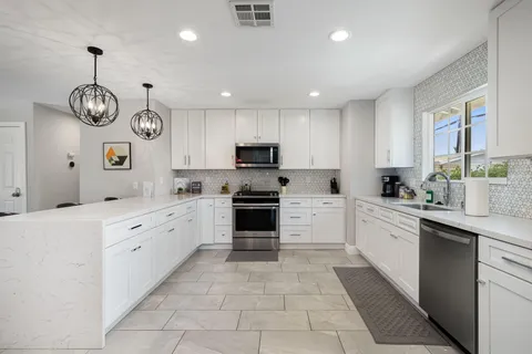 a large kitchen with stainless steel appliances granite countertop a stove and dishwasher