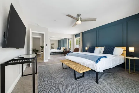 a spacious bedroom with a bed and a flat screen tv