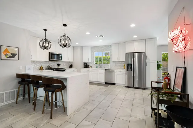 a kitchen with stainless steel appliances granite countertop a sink a stove a refrigerator a microwave oven with a dining table and chairs