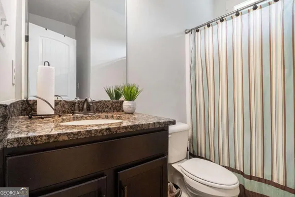a bathroom with a granite countertop sink toilet and mirror
