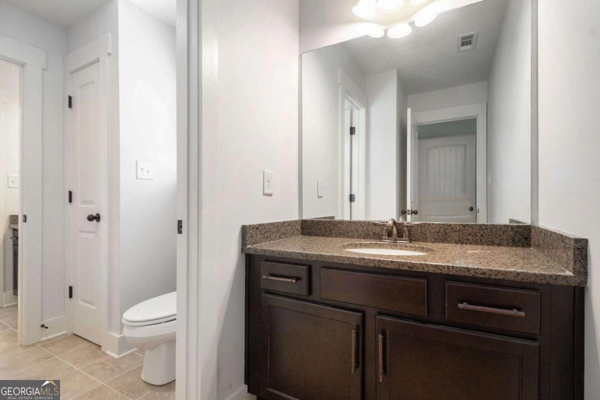 466 Austin Storey Circle Newnan, GA 30263 - Photo 17 of 39 a bathroom with a granite countertop sink a toilet and a mirror