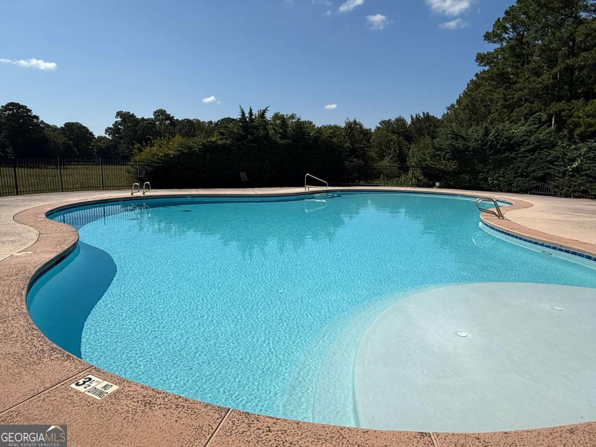 466 Austin Storey Circle Newnan, GA 30263 - Photo 38 of 39 a view of a swimming pool with lake and trees in the background