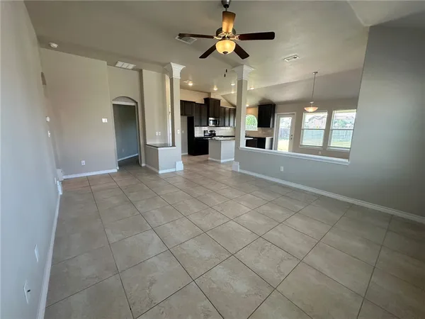 a view of an empty room and a kitchen space a window