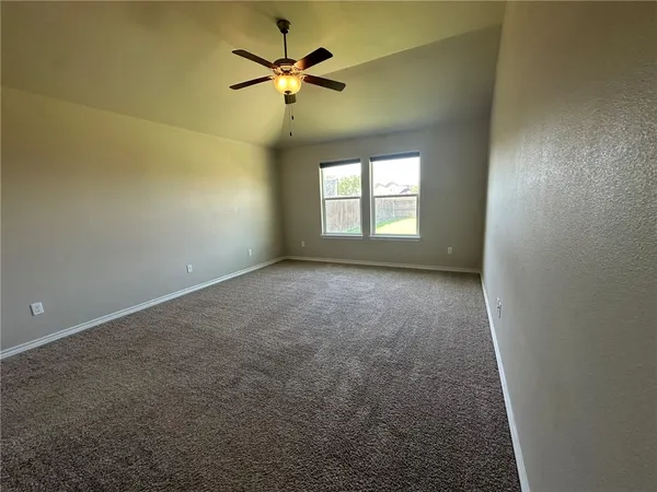 en empty room with windows and chandelier fan