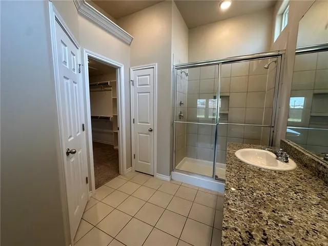 a bathroom with a granite countertop shower a sink and a mirror