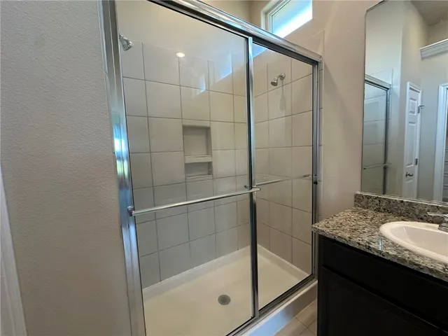 a bathroom with a granite countertop sink mirror and shower