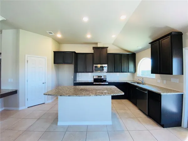 a large kitchen with a large counter top and stainless steel appliances