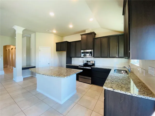 a large kitchen with kitchen island granite countertop a refrigerator and a stove