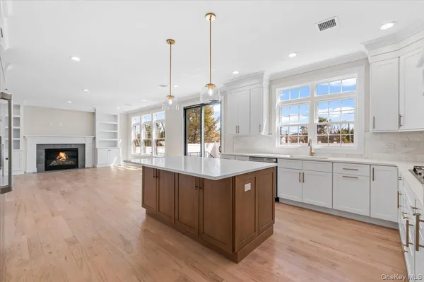 a view of a kitchen with granite countertop a sink and dishwasher cabinets with wooden floor next to windows